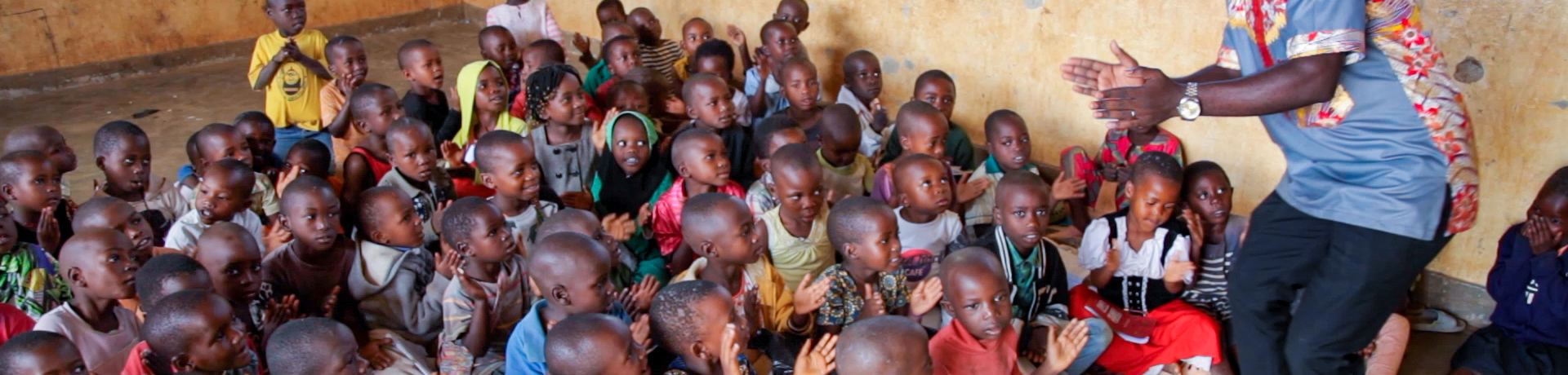 Teacher in front of a class in Uganda. For more information, watch the film "We teach here": https://www.youtube.com/watch?v=9Rk8k-0PVo0&t=116s.